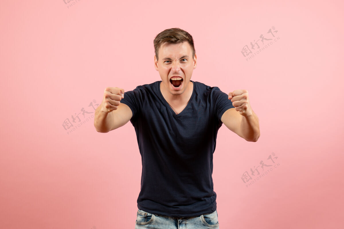 帅哥正面图身着蓝色t恤的年轻男性在粉色背景上激情洋溢男性情感色彩模特人类男性年轻男性成人
