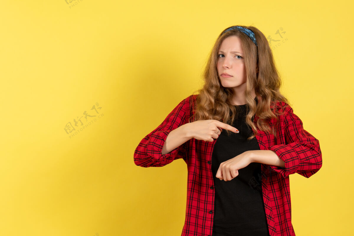 手指正面图：穿着红色格子衬衫的年轻女性 手腕指向黄色背景的模特女孩人类女人的颜色手腕女孩漂亮