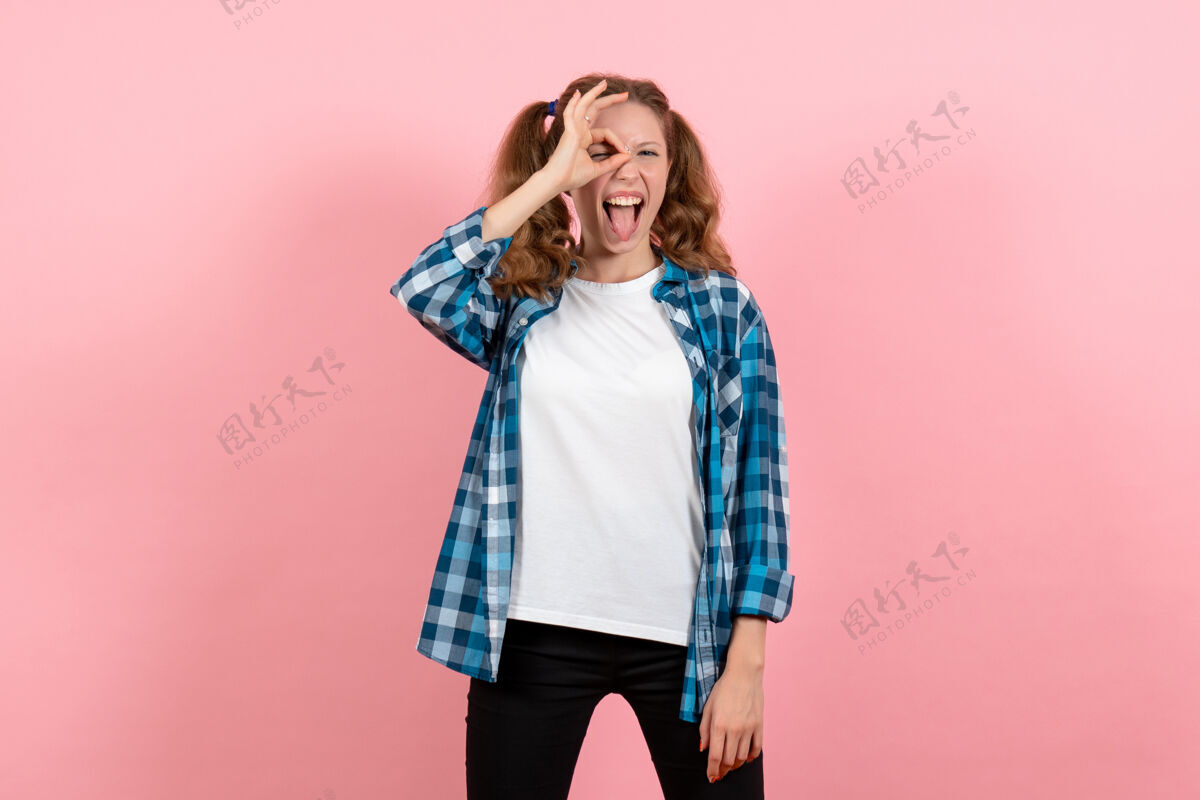 年轻女性正面图穿着格子衬衫的年轻女性在粉色桌子上摆姿势年轻女性情感模特儿颜色肖像姿势年轻人