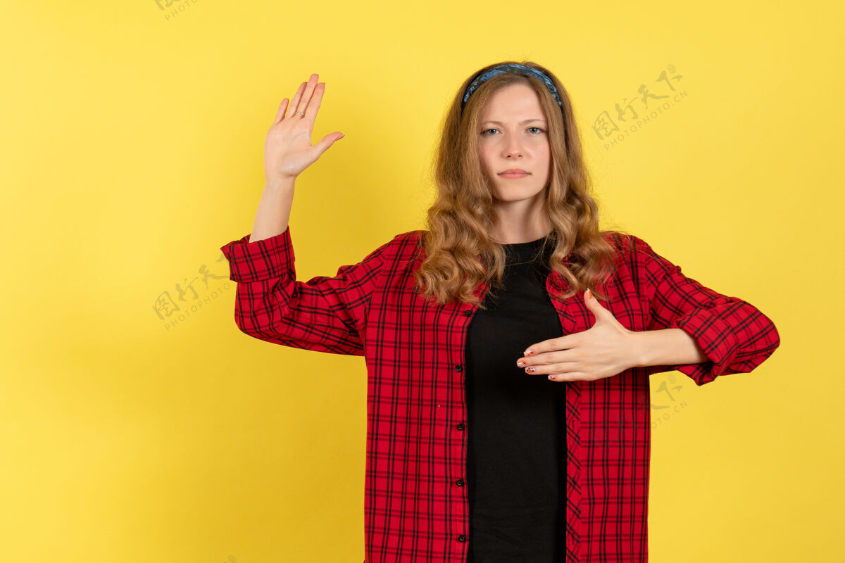 年轻的女性正面图：穿着红色格子衬衫的年轻女性站在黄色背景上 摆姿势 女孩颜色 女性模特 人类站着肖像人