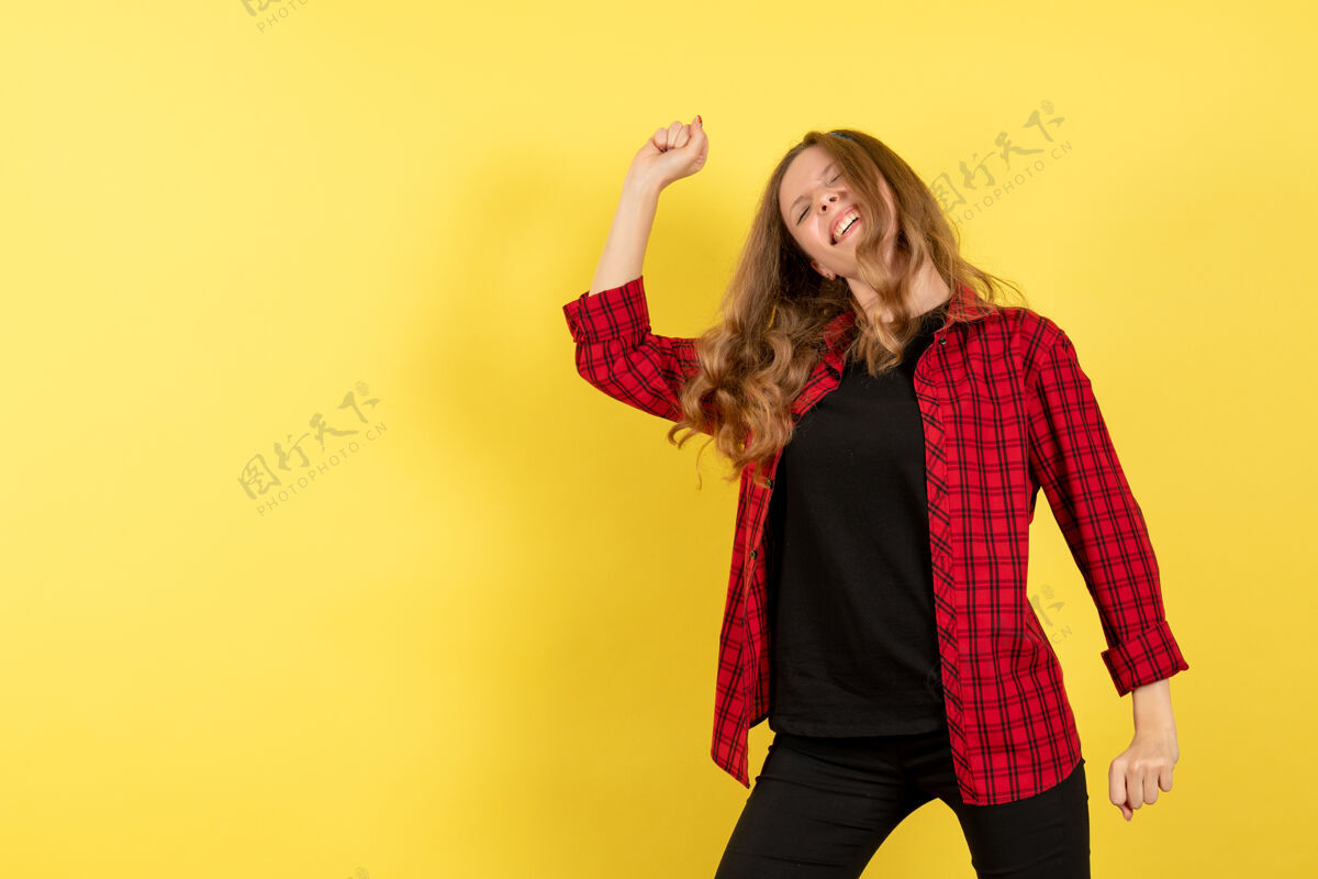 舞蹈正面图身着红色格子衬衫的年轻女性在黄色背景上翩翩起舞人色模特女人感慨衬衫肖像年轻女性