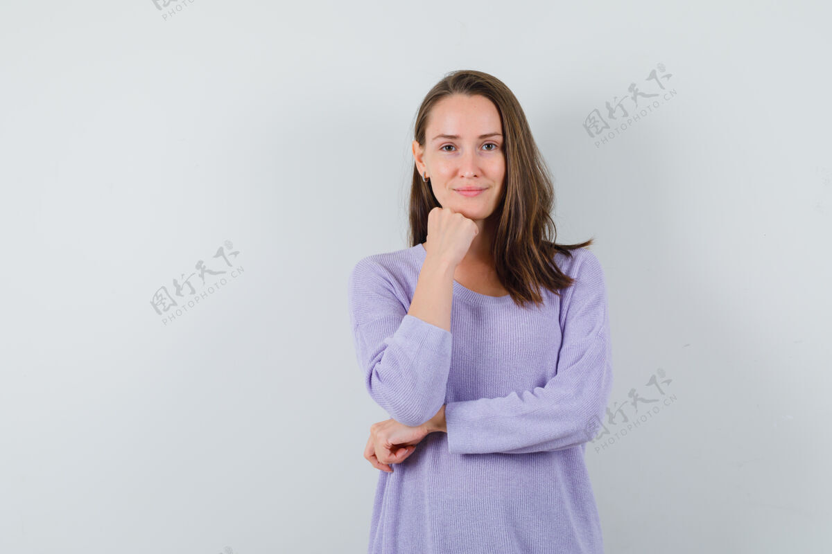 衬衫一位年轻的女性斜靠在她的拳头边对着镜头微笑 身穿淡紫色上衣 看上去很清新卷曲而自信