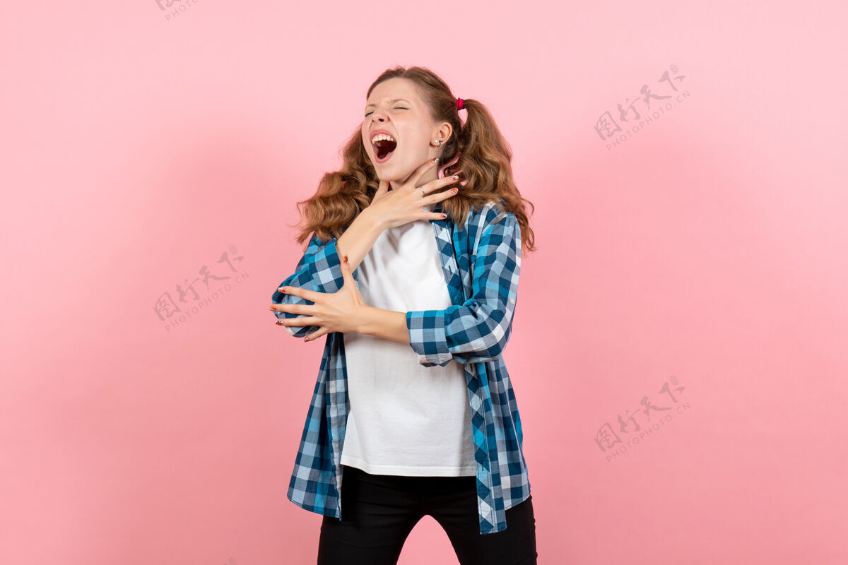 人正面图：穿着格子衬衫的年轻女性在粉色办公桌上摆姿势女人孩子青春色彩情感模型格子青年衬衫