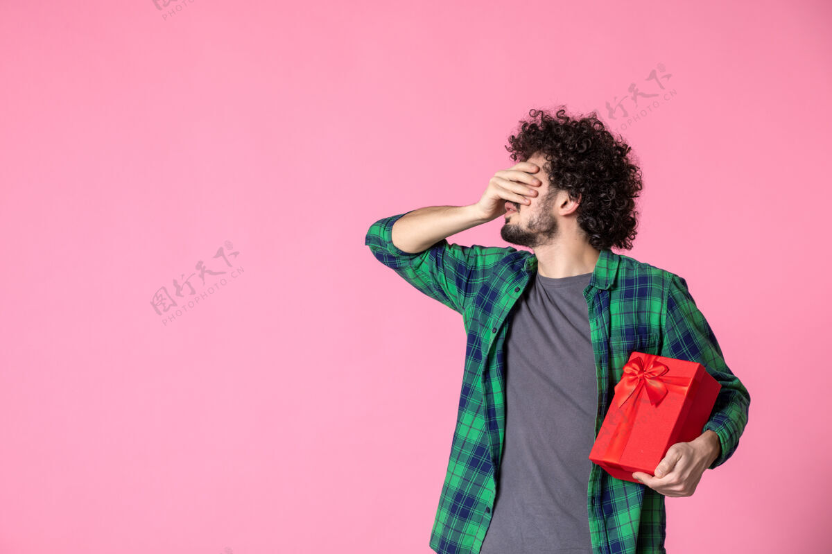 礼盒浅粉色墙上红色包裹的年轻男性正面图衬衫礼物男人