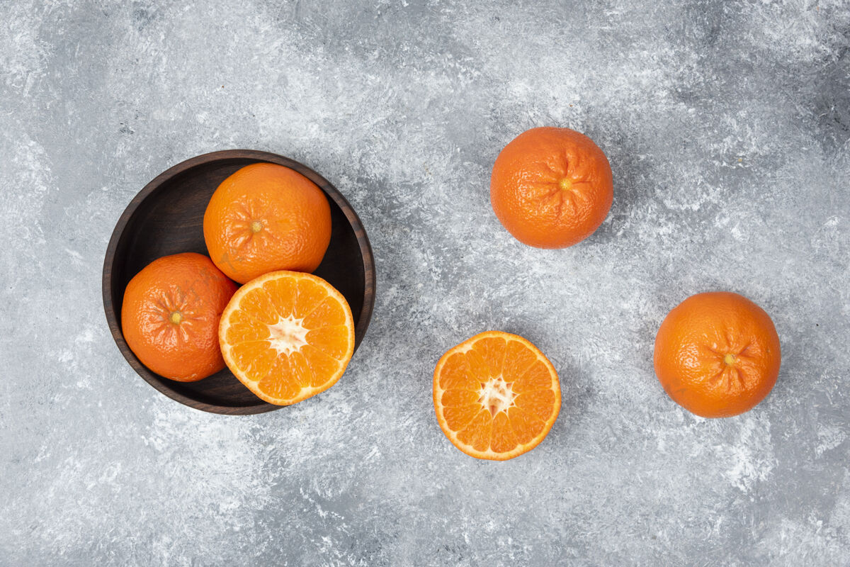 甜点石桌上摆满了橙子汁的木碗成熟热带柑橘
