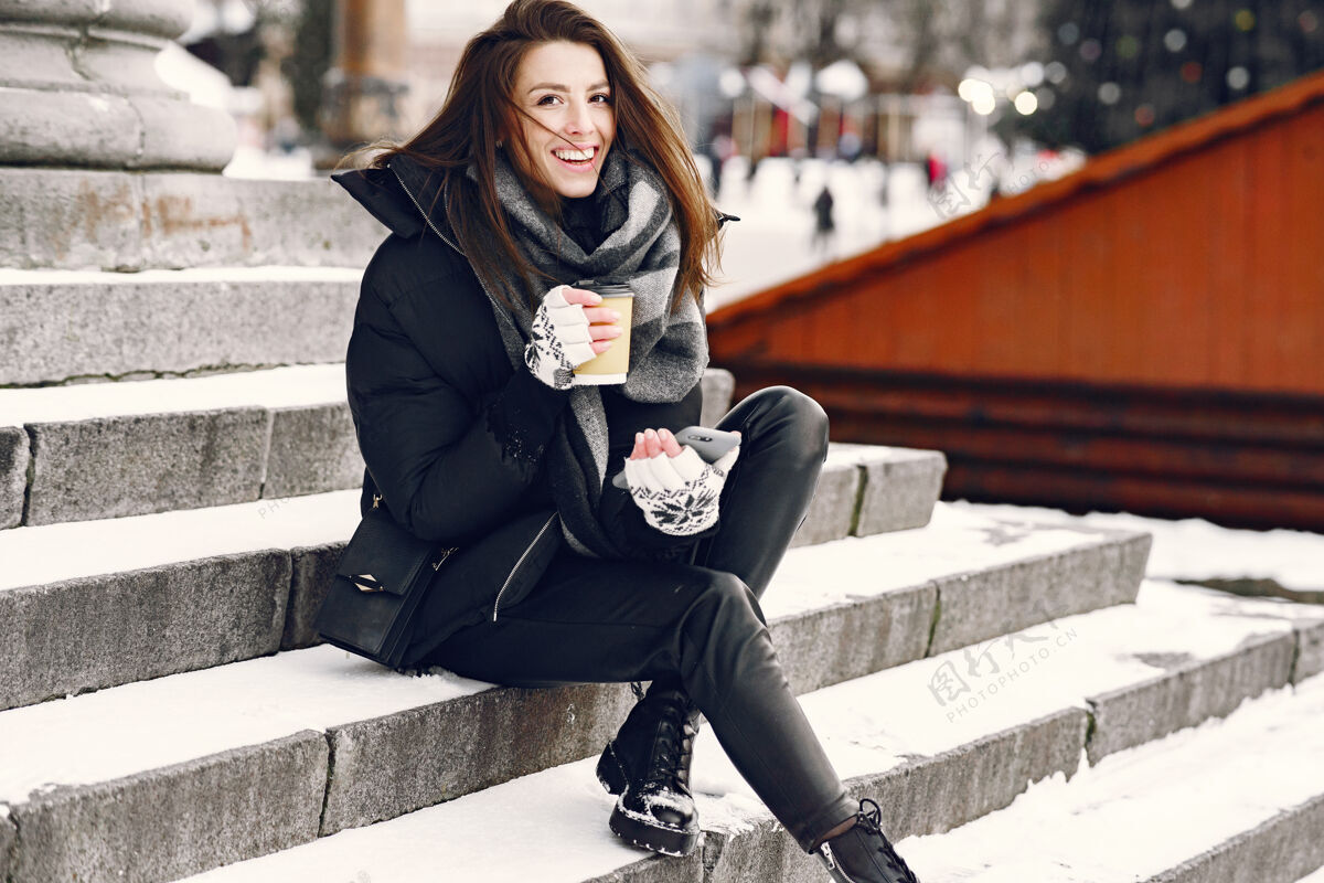 模型一个穿着黑色夹克 喝着外卖咖啡的女人的特写肖像外套雪围巾