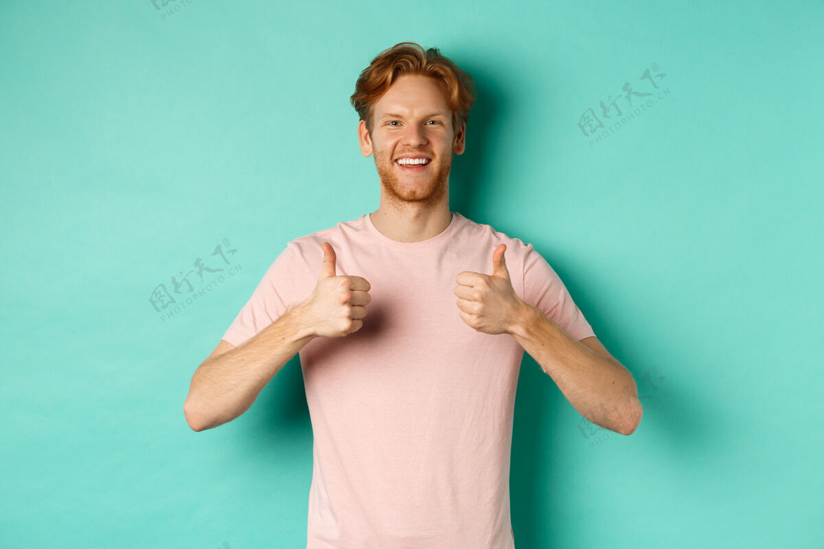 崇拜喜气洋洋的红胡子男人 竖起大拇指 喜欢并赞同某件事 赞美宣传片 站在绿松石色的背景下自信学生胡须