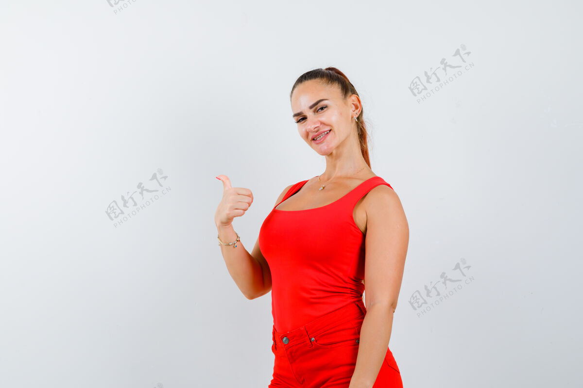 微笑穿红色单品的年轻女士 红色裤子 大拇指朝上 看起来很高兴 正前方节日季节夏天