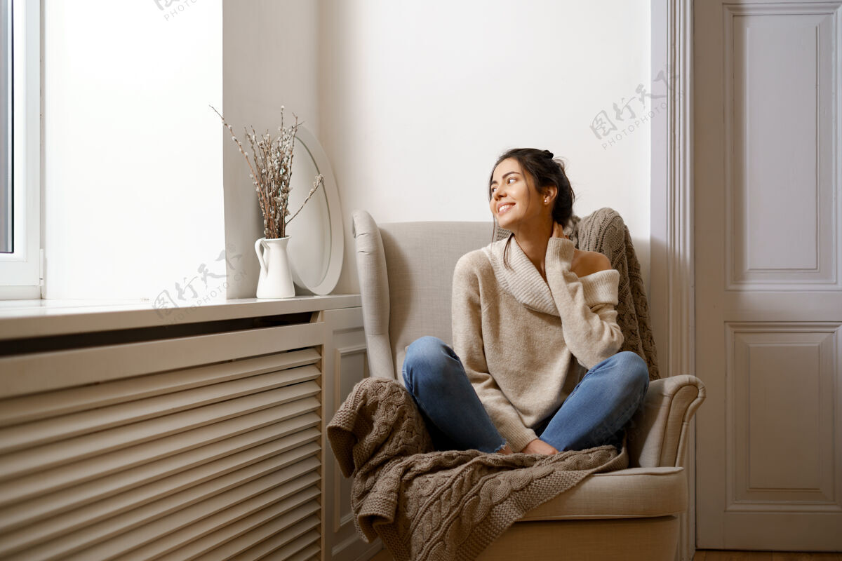 扶手椅穿着时髦时髦服装的微笑女士坐在扶手椅上 微笑着 坐在室内放松的气氛中室内欢乐放松