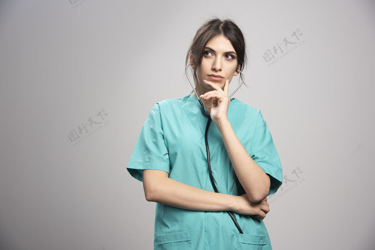 年轻人女医生拿着听诊器站在灰色的地板上个人工作职业