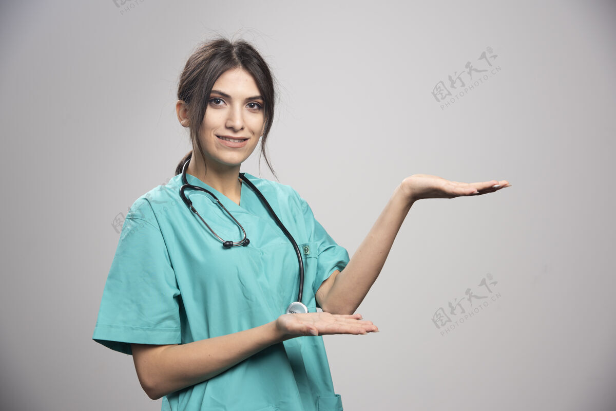 妇女穿制服的女医生在灰色的床上摆姿势疾病工作医院