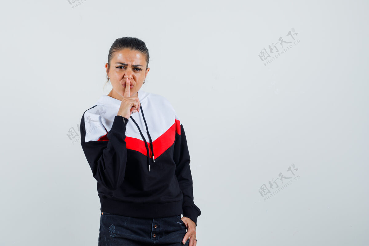 成人身着五颜六色运动衫的年轻女士展示着沉默的姿态 表情严肃正面视图手势肖像女士