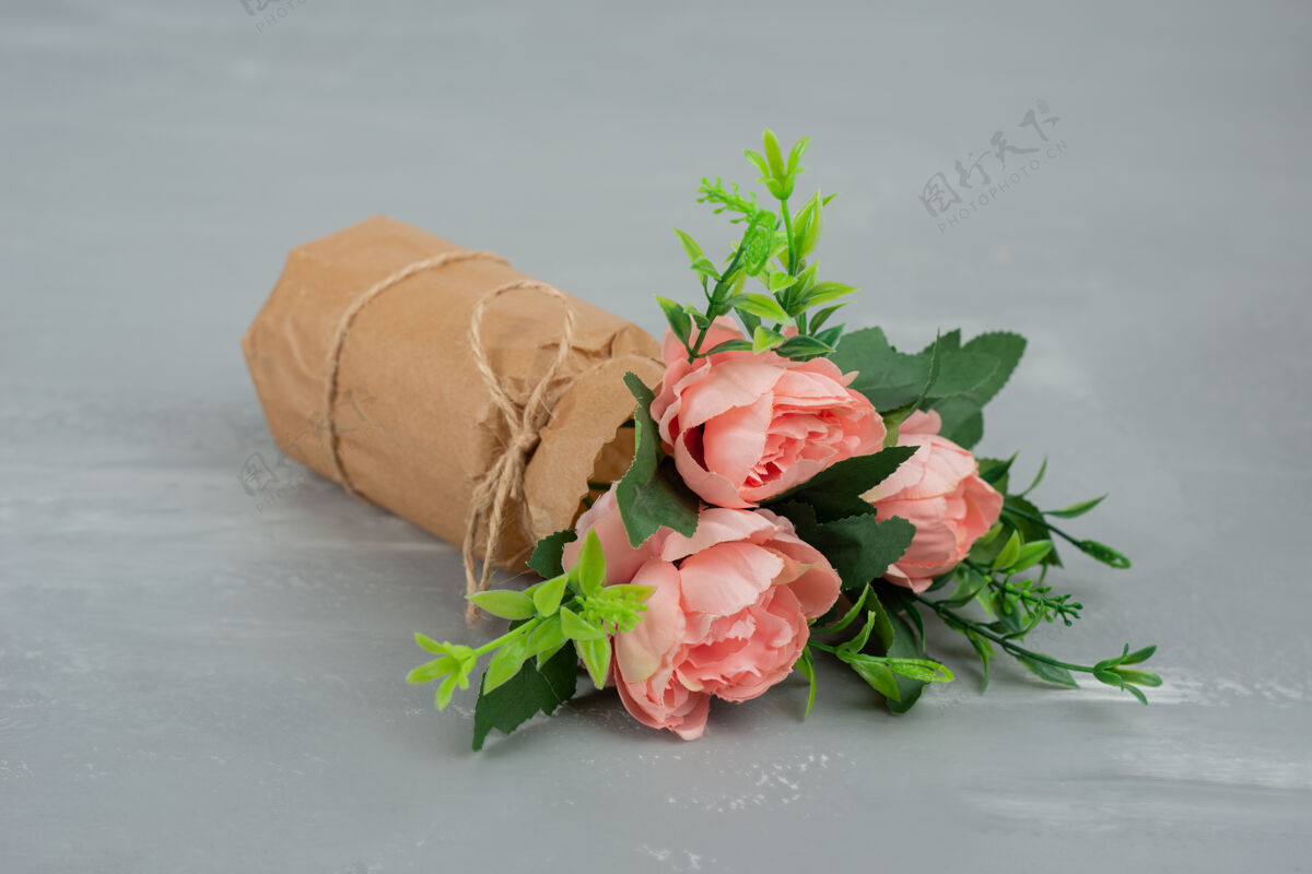 花束在灰色的桌子上放着一束美丽的粉红玫瑰叶玫瑰安排