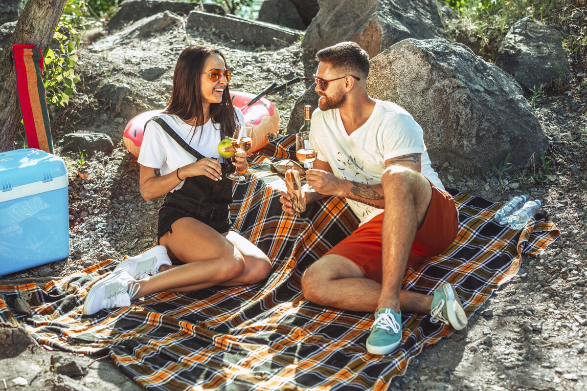 人一对年轻的情侣在阳光明媚的日子里在河边野餐蜜月夫妻休闲