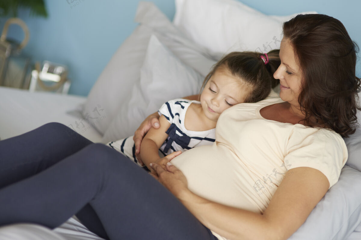 怀孕女儿和妈妈在等孩子人类腹部躺下床