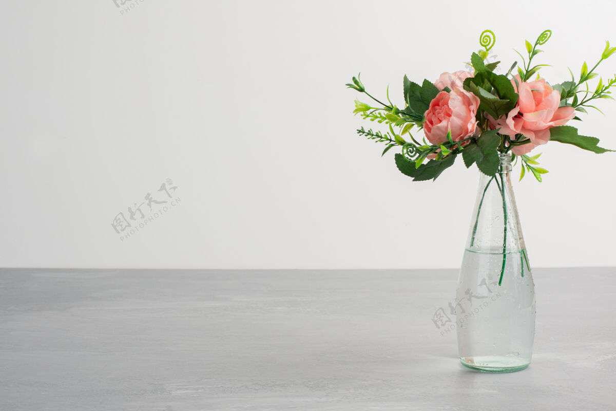 花瓣一个玻璃花瓶里有粉红色的花和绿色的叶子自然花瓶花