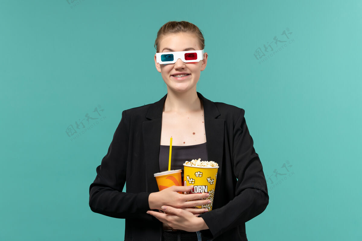 电影正面图：戴着d型太阳镜拿着爆米花看电影的年轻女性爆米花太阳镜看