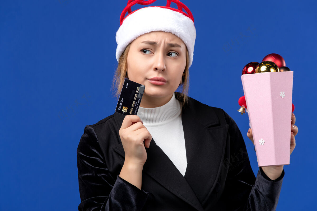 商务女性前视图：带着树玩具和银行卡的年轻女士在蓝色地板上过年年轻女士圣诞节职业