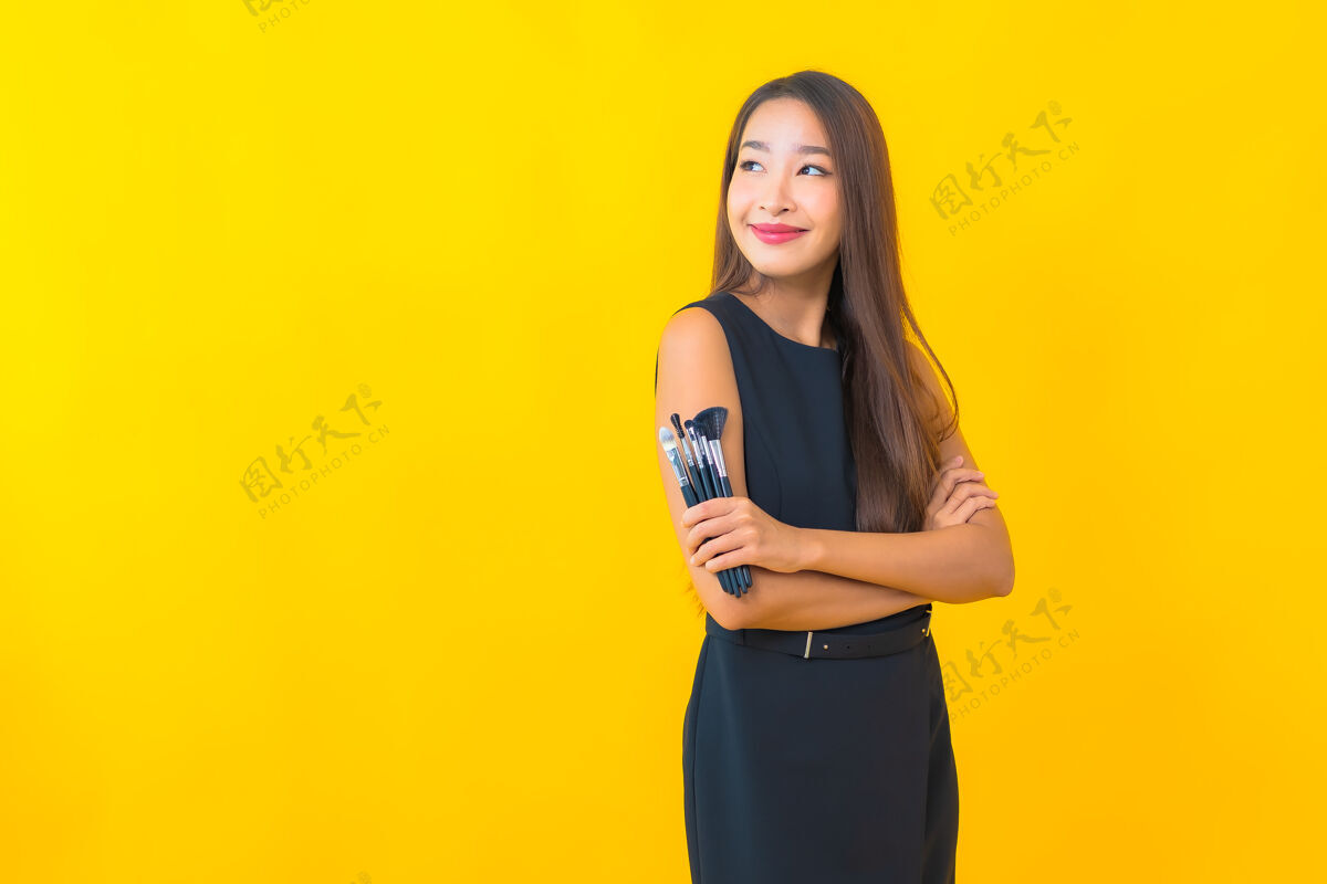 相机在黄色背景上用化妆刷描绘美丽的亚洲女商人在线女孩博客