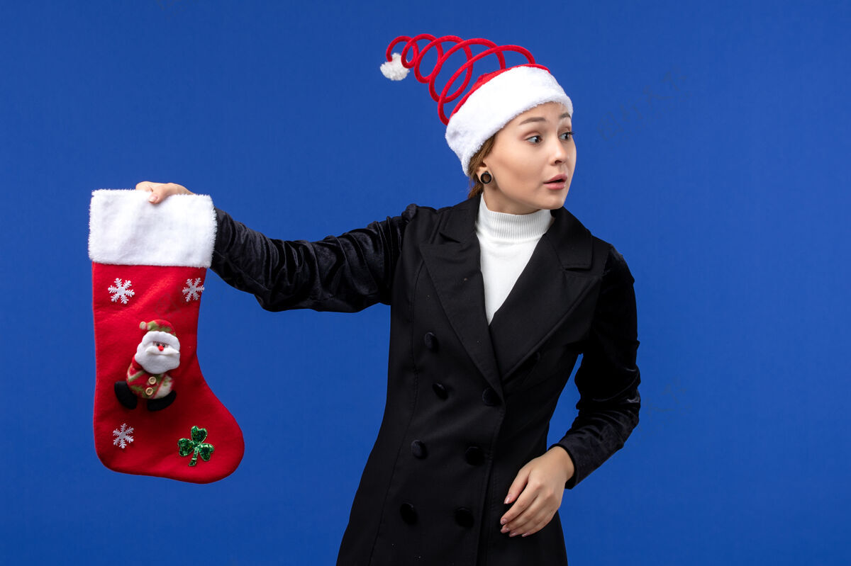 夏娃正面图：年轻女子手持大圣诞袜站在蓝色墙壁上过年过节大人职业