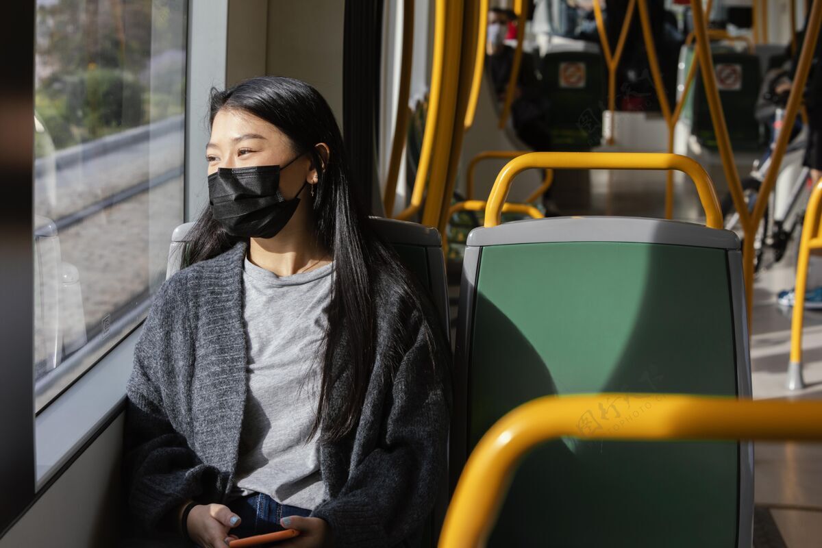 休闲公共汽车上戴着面具的年轻女子女人面具公共交通