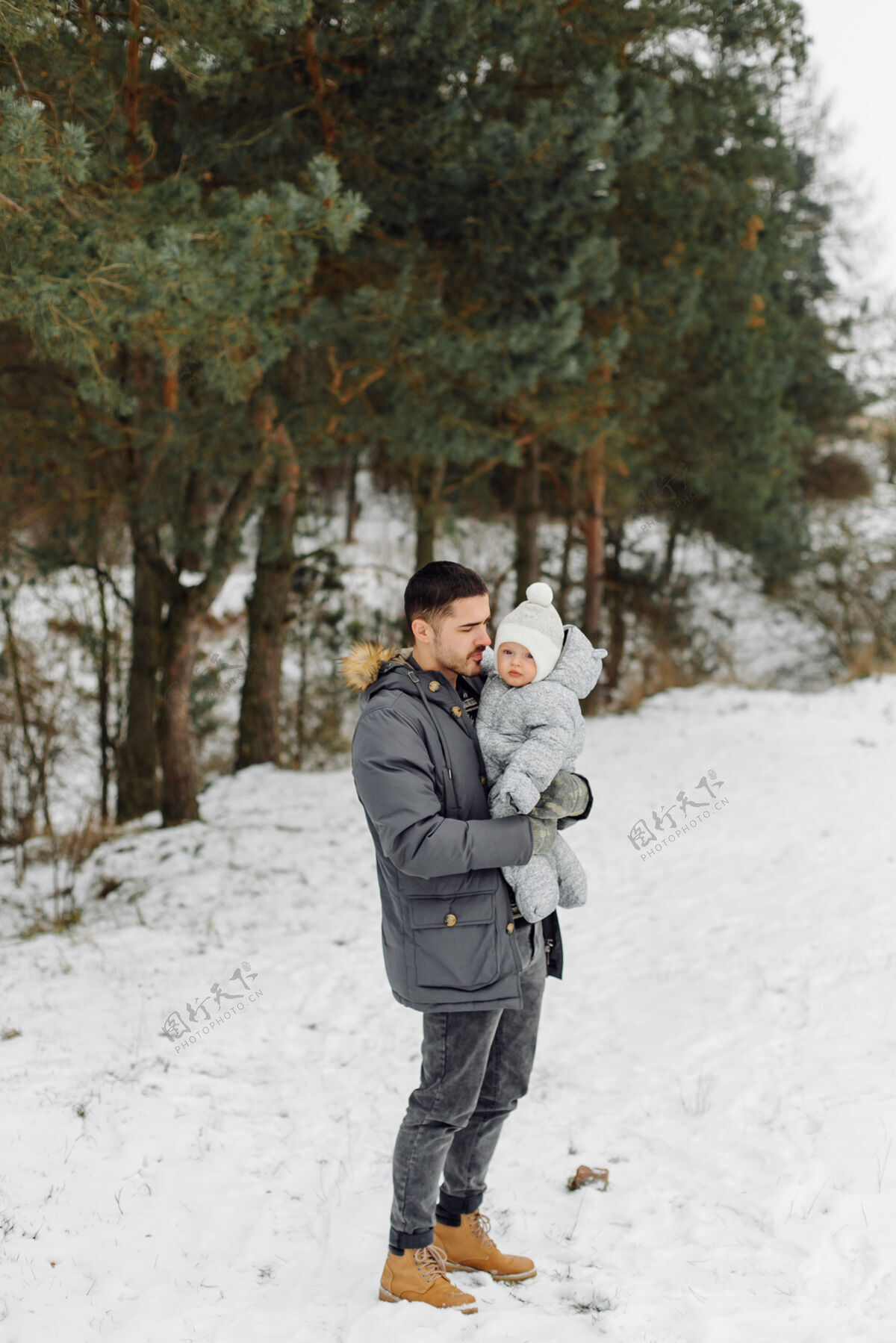 父母在一个阳光明媚的日子里 一家人在雪中散步 在冬季公园里玩得开心 互相拥抱 面带微笑休闲乐趣朋友
