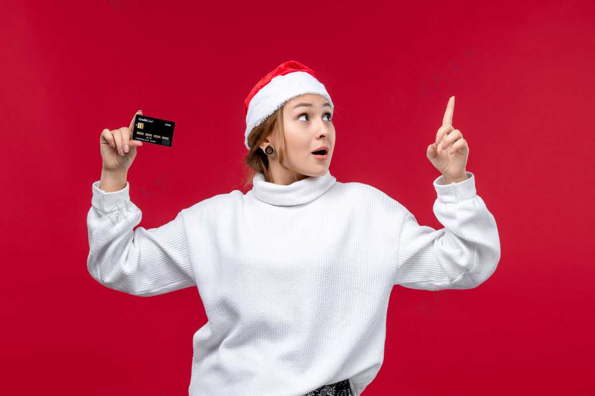 圣诞节前视图年轻女子手持浅红色背景的银行卡浅红色男性卡片