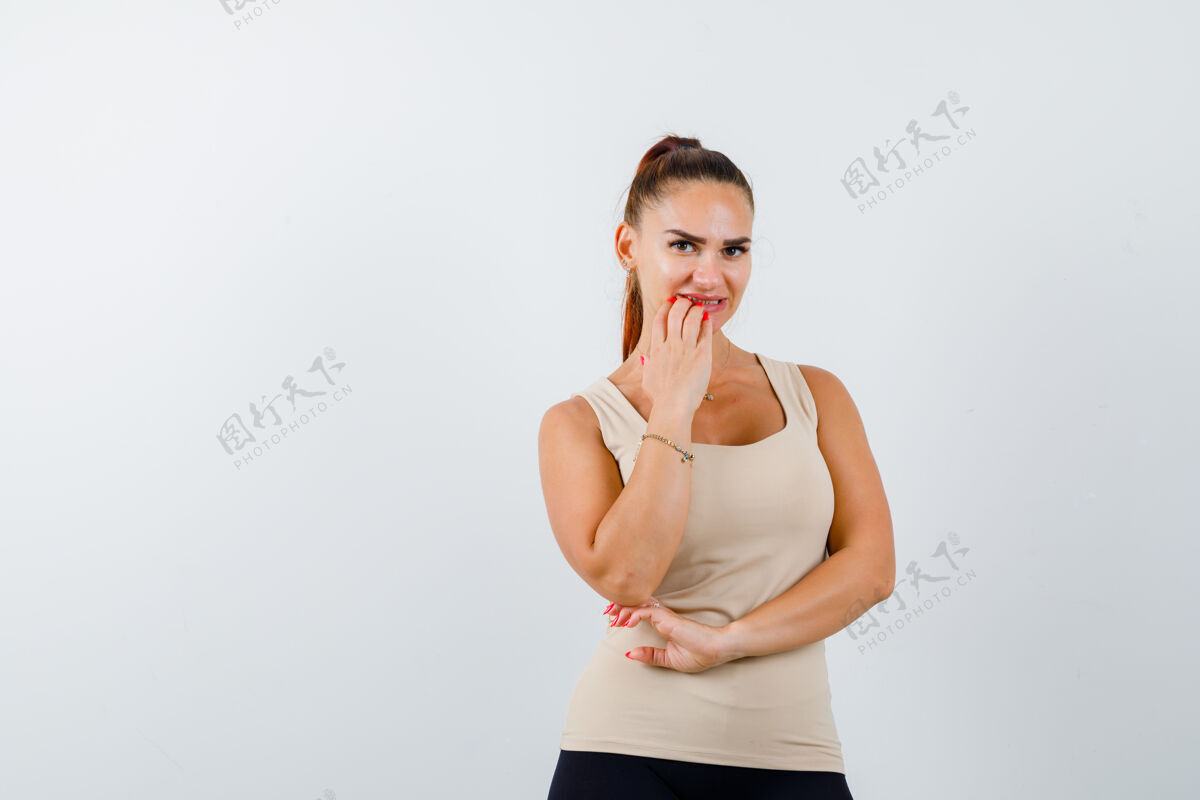 想法在米色的背心上咬指甲的年轻女性的肖像 看深思熟虑的前视图前面表情坦克