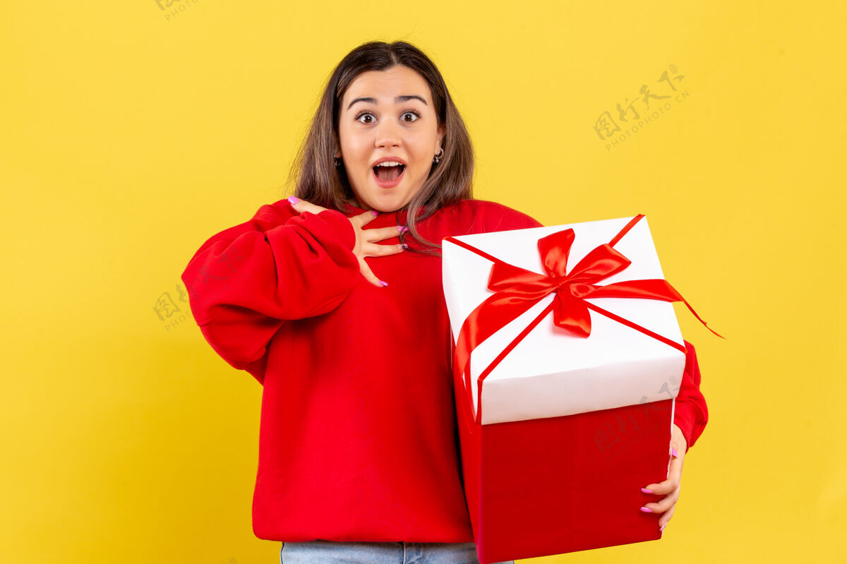 成人前视图年轻女子手持圣诞礼物黄色背景礼物圣诞节观看