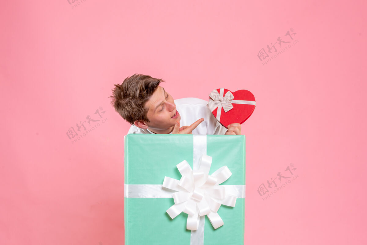 粉色正面图年轻男性在粉红色背景上赠送礼物庆祝丝带正面