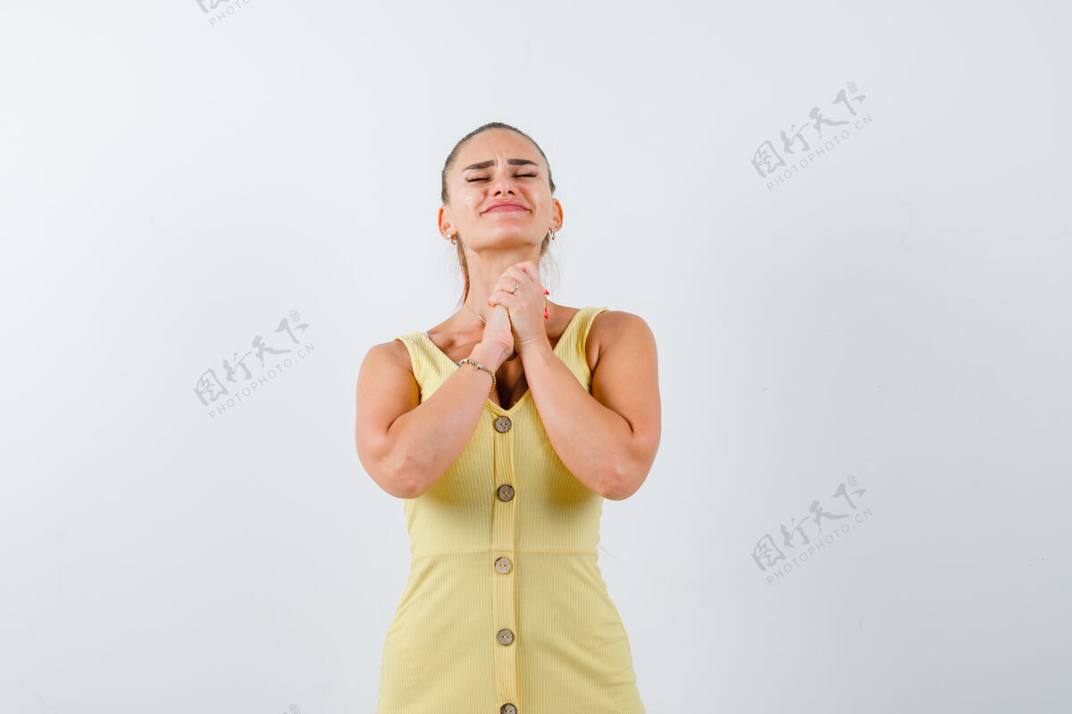 手势身穿黄色连衣裙的年轻女子双手合十祈祷 看上去充满希望 正对着前方侧线前进安静