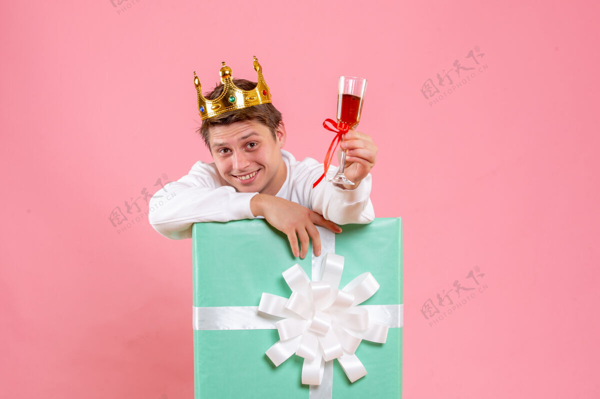 乐趣正面图：年轻男性 戴着皇冠 一杯酒 背景为粉色情感五彩纸屑圣诞
