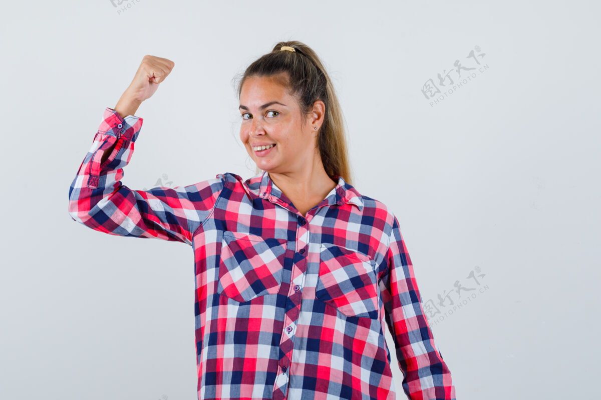 一个年轻女子的肖像展示肌肉手臂在休闲衬衫和期待自豪的前视图衬衫女人微笑