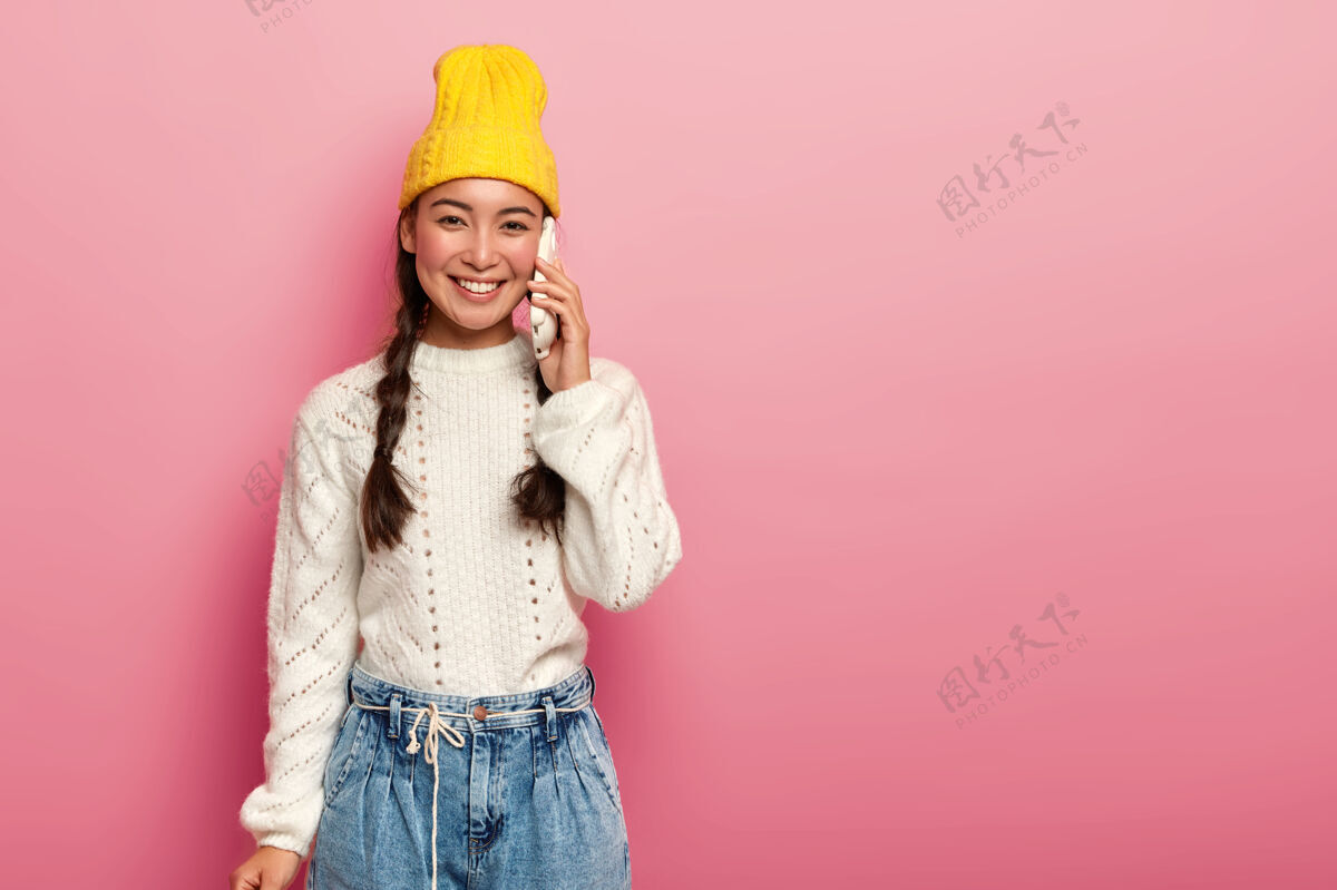 毛衣快乐积极的混血少女喜欢通过手机交流 戴着时髦的黄色帽子休闲手机设备