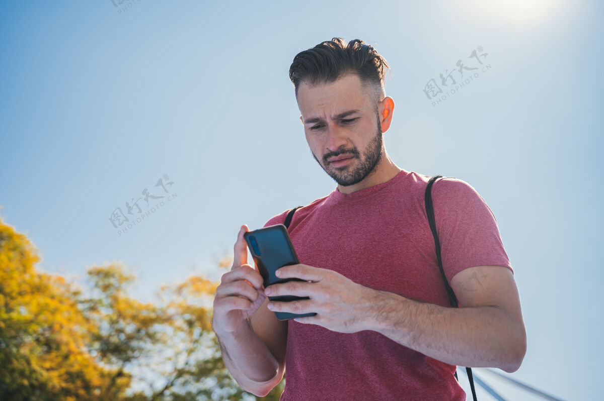 白天一个年轻人在训练前检查手机的低角度镜头白种人男性锻炼