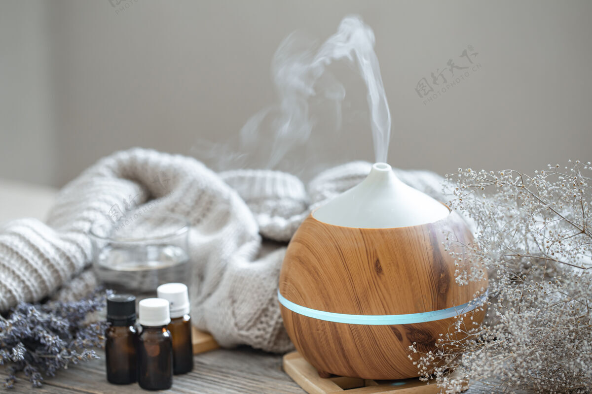 蒸汽现代芳香油扩散在木材表面与针织元素 水和油在罐子薰衣草芳香疗法设备