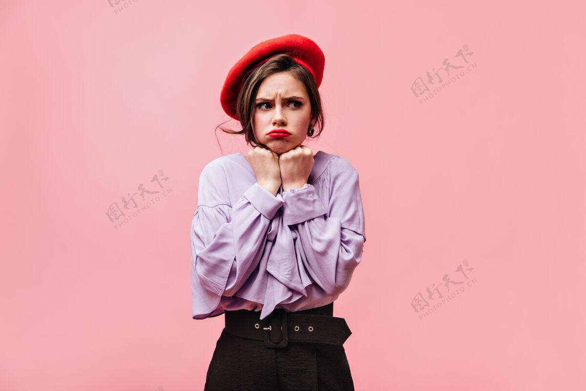姿势一个穿着紫色上衣 红色贝雷帽和裤子的漂亮女孩在粉色背景上摆出一副很不礼貌的姿势衬衫成人女孩