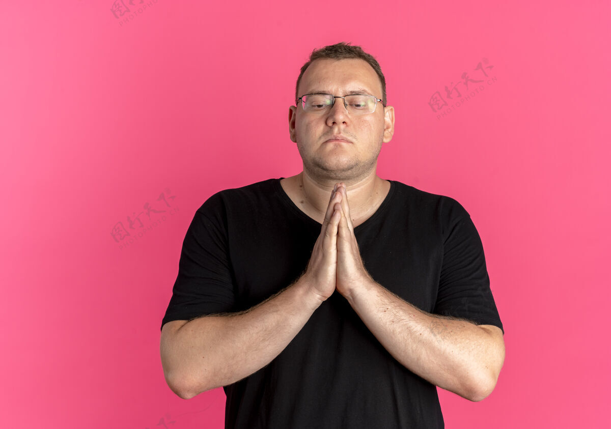喜欢戴眼镜的超重男子身穿黑色t恤 双手合十 像祈祷一样 脸上带着希望的表情一起祈祷男人