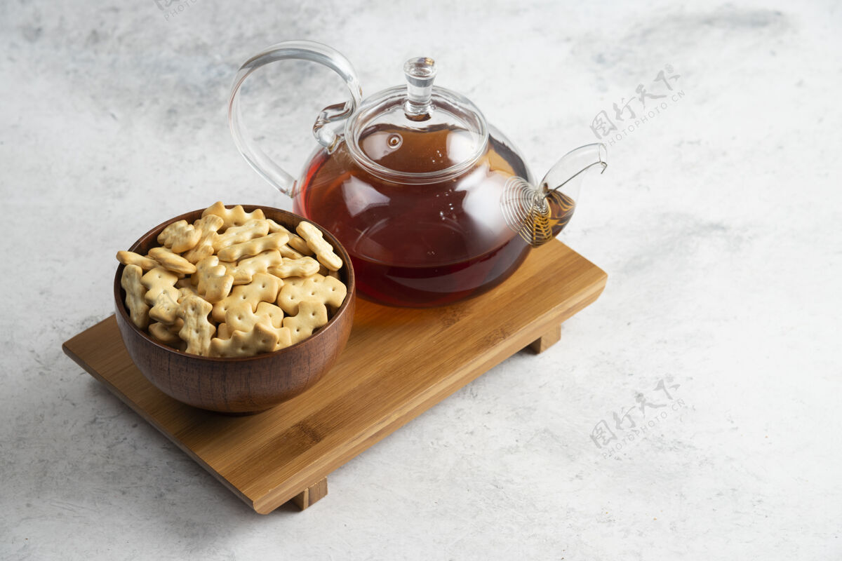 糕点一个玻璃茶壶和装满饼干的木碗壶美味玻璃