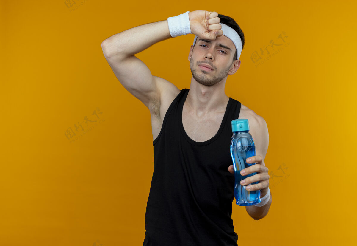 看站在橘色的墙上 戴着头巾 拿着一瓶水 看上去筋疲力尽的年轻人奶瓶筋疲力尽运动