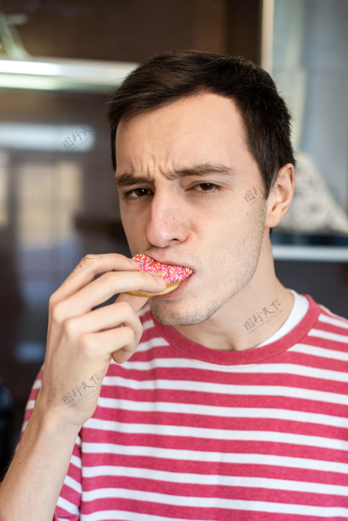 成熟一个严肃的脸在厨房里吃甜甜圈的男人严肃中年消极