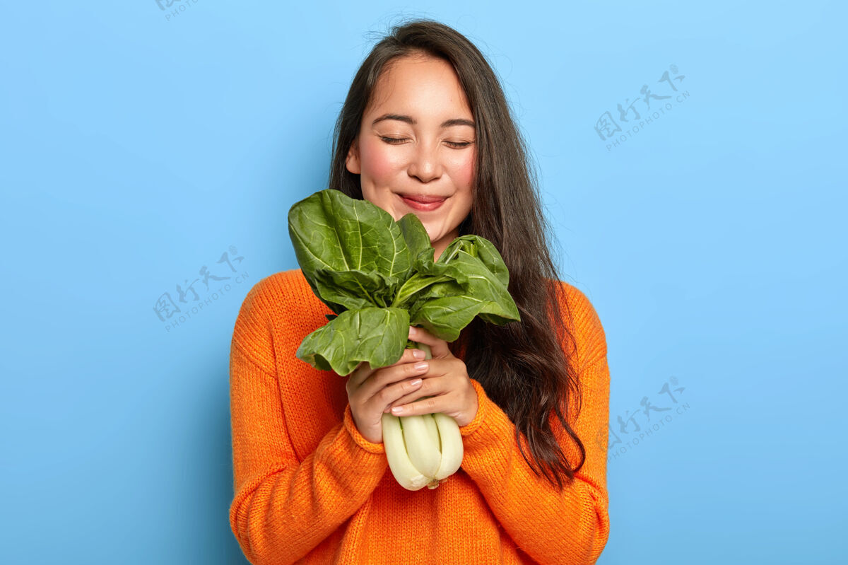 站立手持绿叶的年轻女子健康饮食微笑
