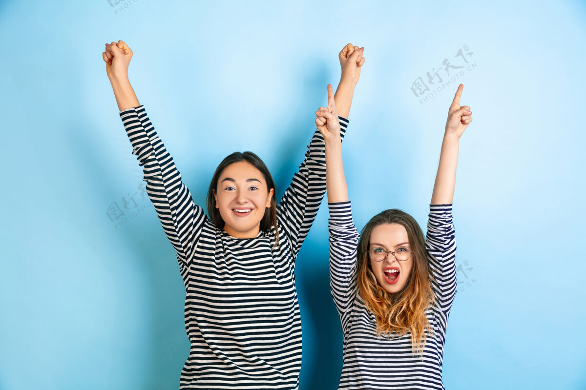 关系快乐的赢家 指点年轻感性的女人被隔离在蓝色的墙壁上人类情感的概念 面部表情 友谊 广告穿着休闲服的漂亮白人模特指向微笑情绪