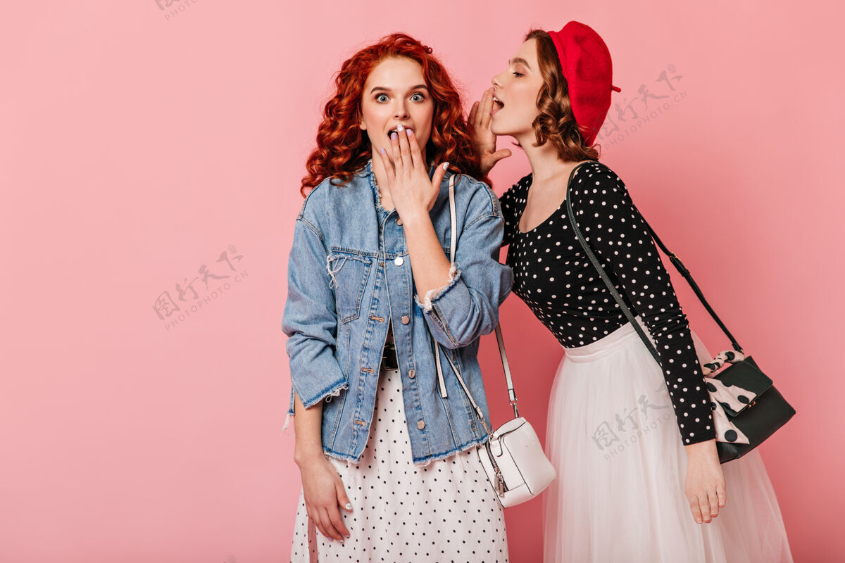 交谈听朋友说话的姜女震惊了两个女人在粉色背景下说话友谊表情红发
