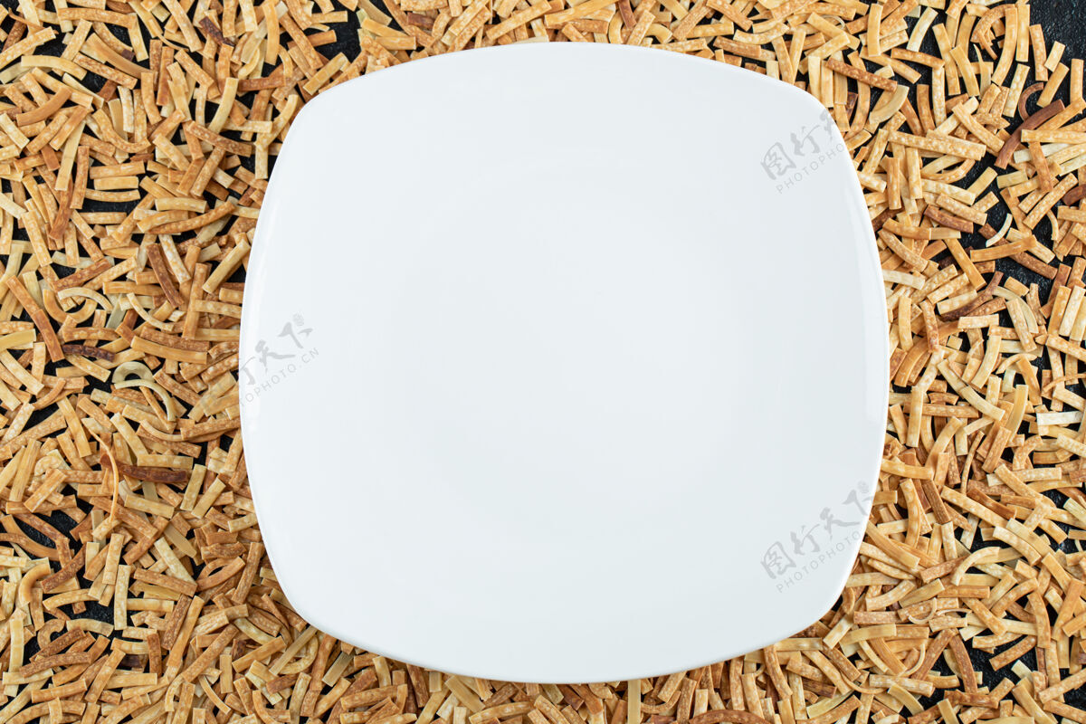 生的生面食散落在白色盘子里烹饪干的食物