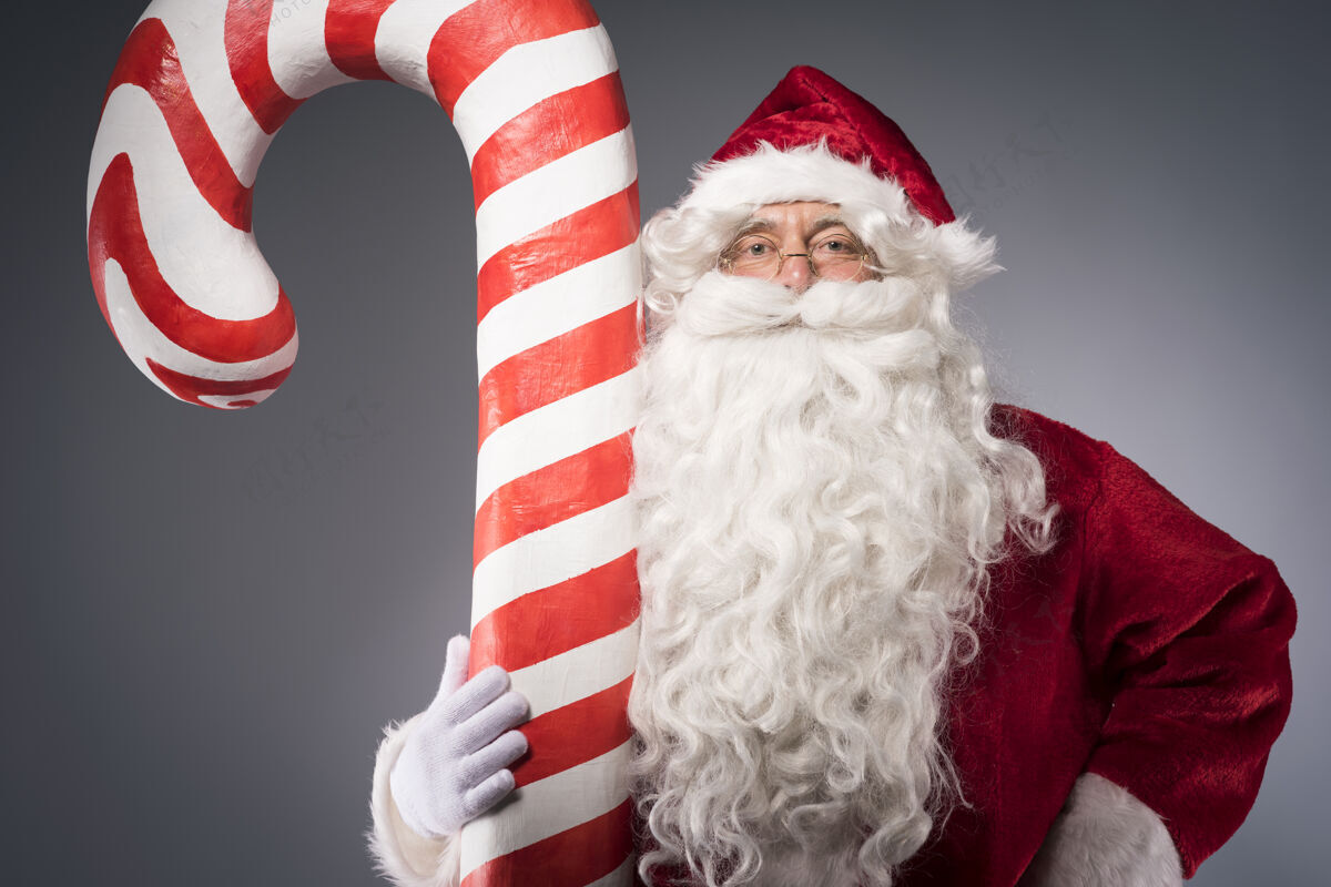 欢乐圣诞老人手里拿着一根巨大的糖果棒背景服装室内