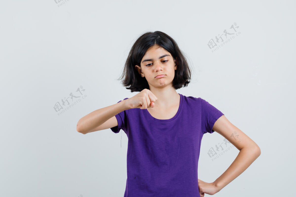 自信小女孩看着她紧握的拳头在t恤衫上 看起来很自信 积极女握紧