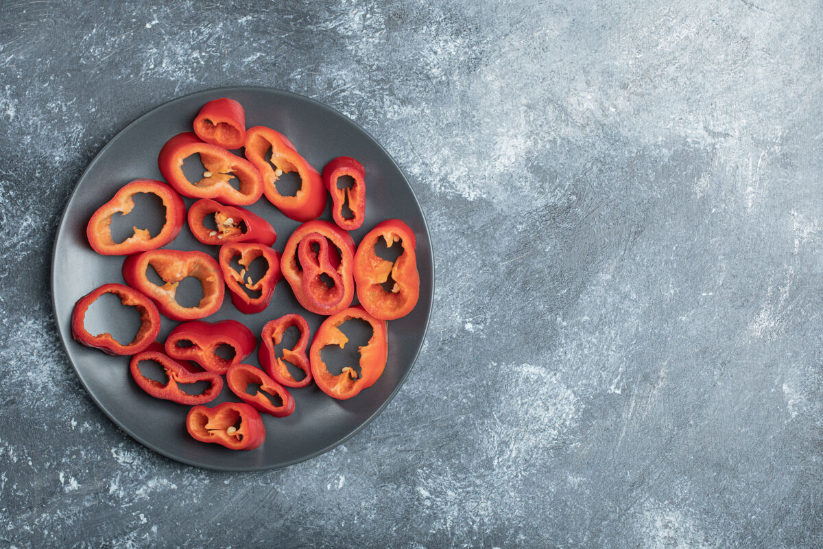 甜味黑盘子上的红椒片成熟堆红色