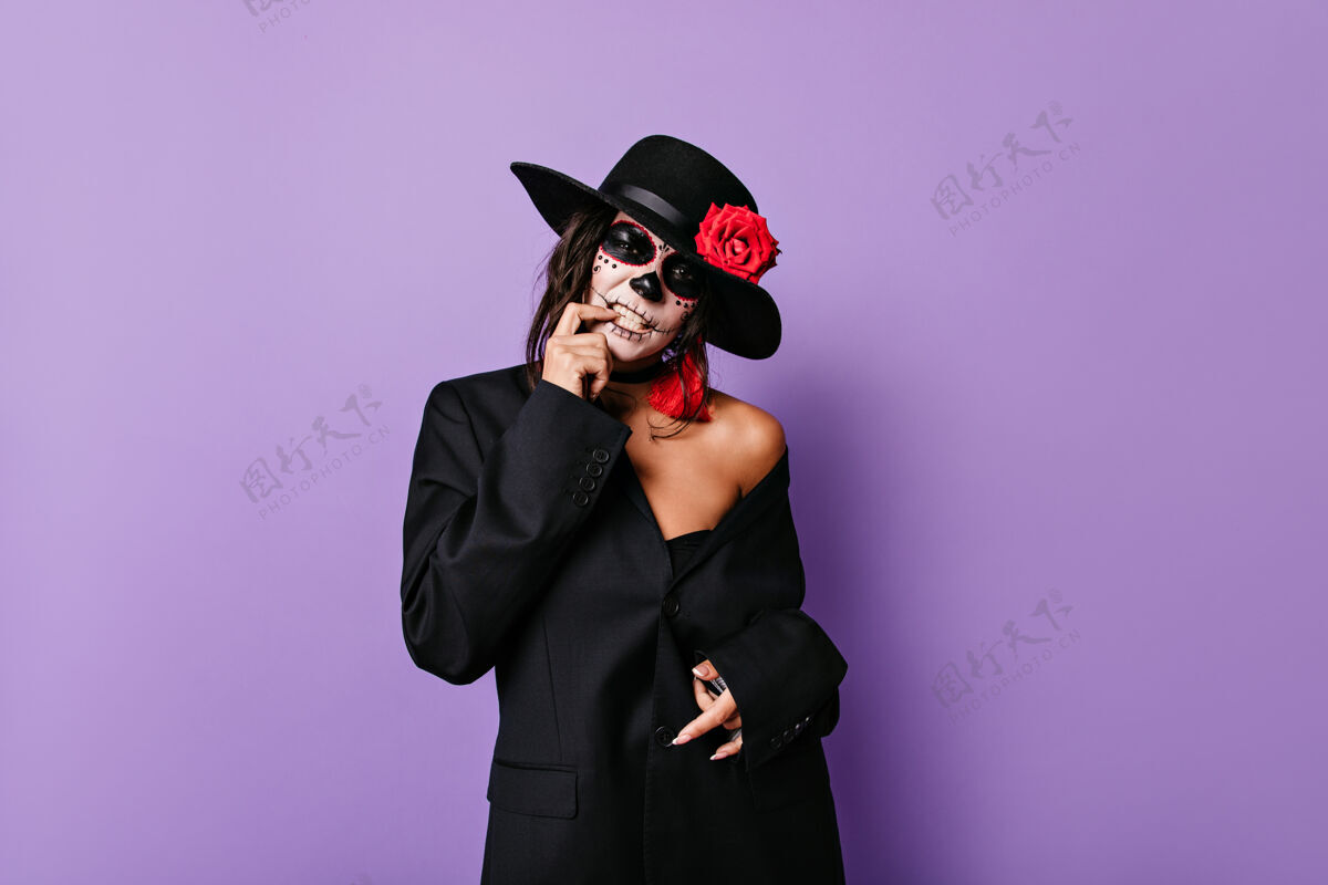 墨西哥可怜的黑手党女人在紫丁香隔离墙上摸着她的牙齿 戴着头骨面具摆姿势死亡女人女