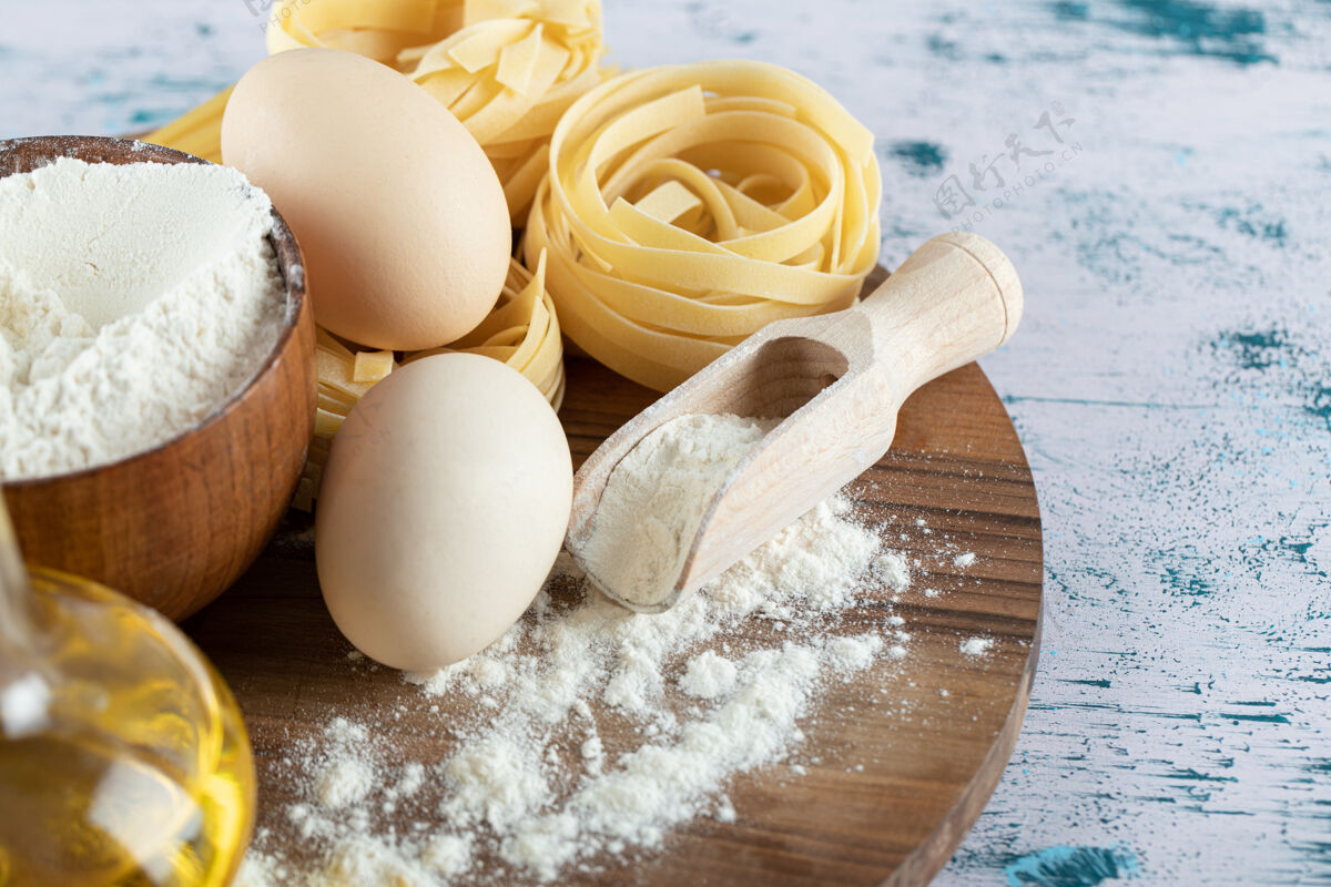 意大利面生面食用油 鸡蛋和一碗面粉放在木板上烹饪生的通心粉